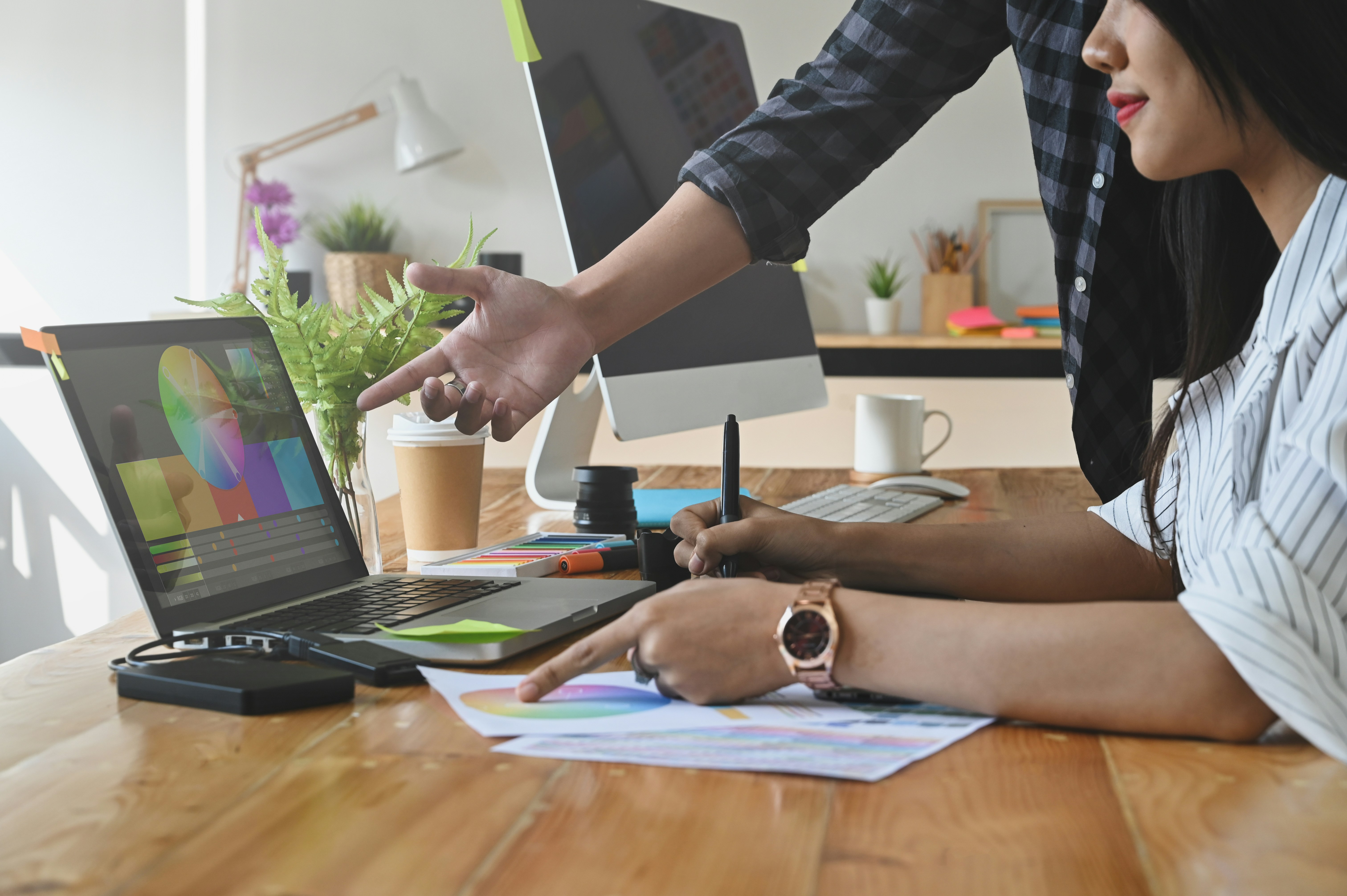 Learn@Home - Zwei Personen arbeiten am Schreibtisch; eine erklärt etwas am Laptop, die andere macht Notizen.