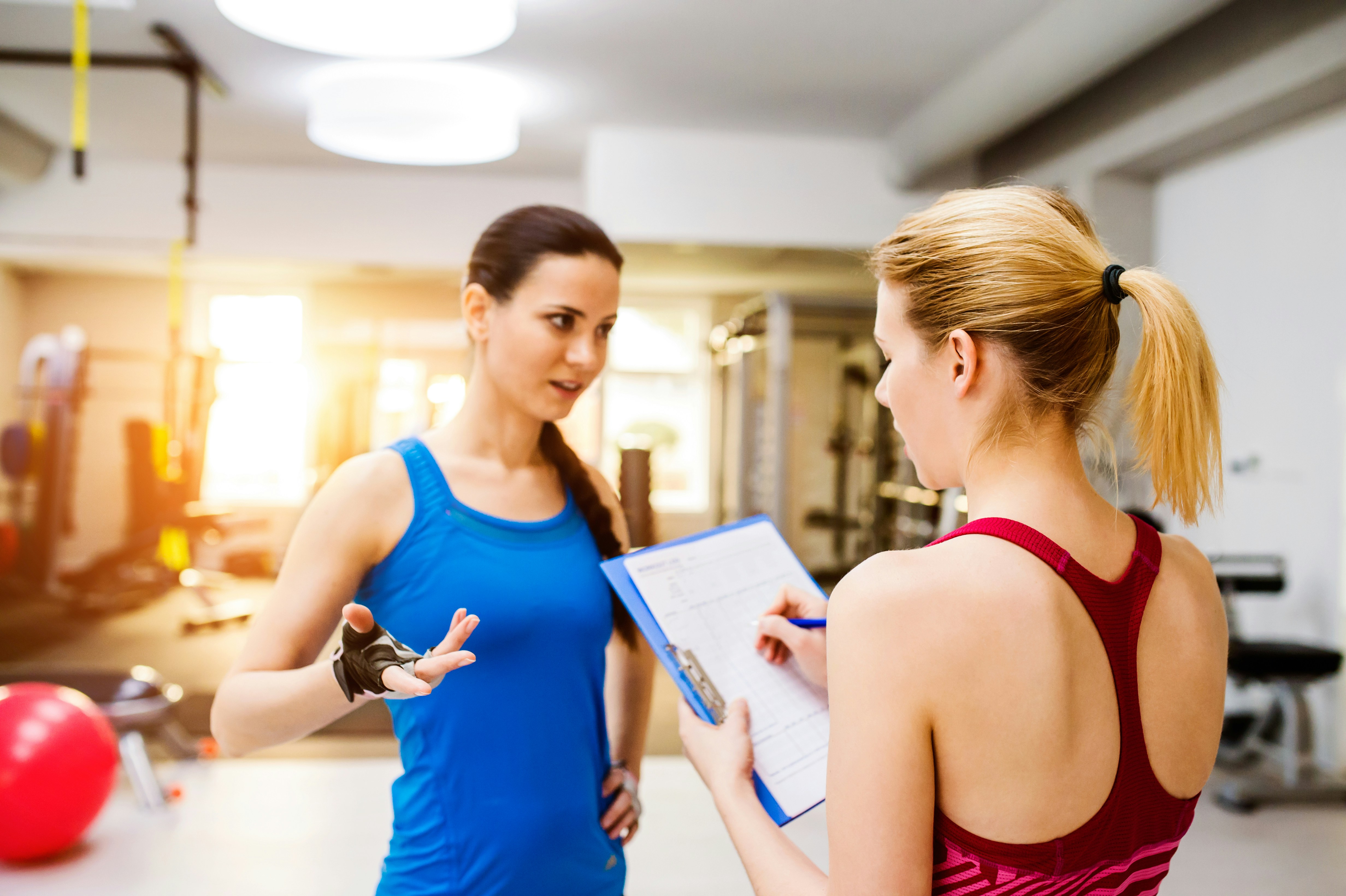 Learn@Home - Sportmentaltrainerin im Gespräch mit einer Sportlerin während einer Trainingseinheit im Fitnessstudio