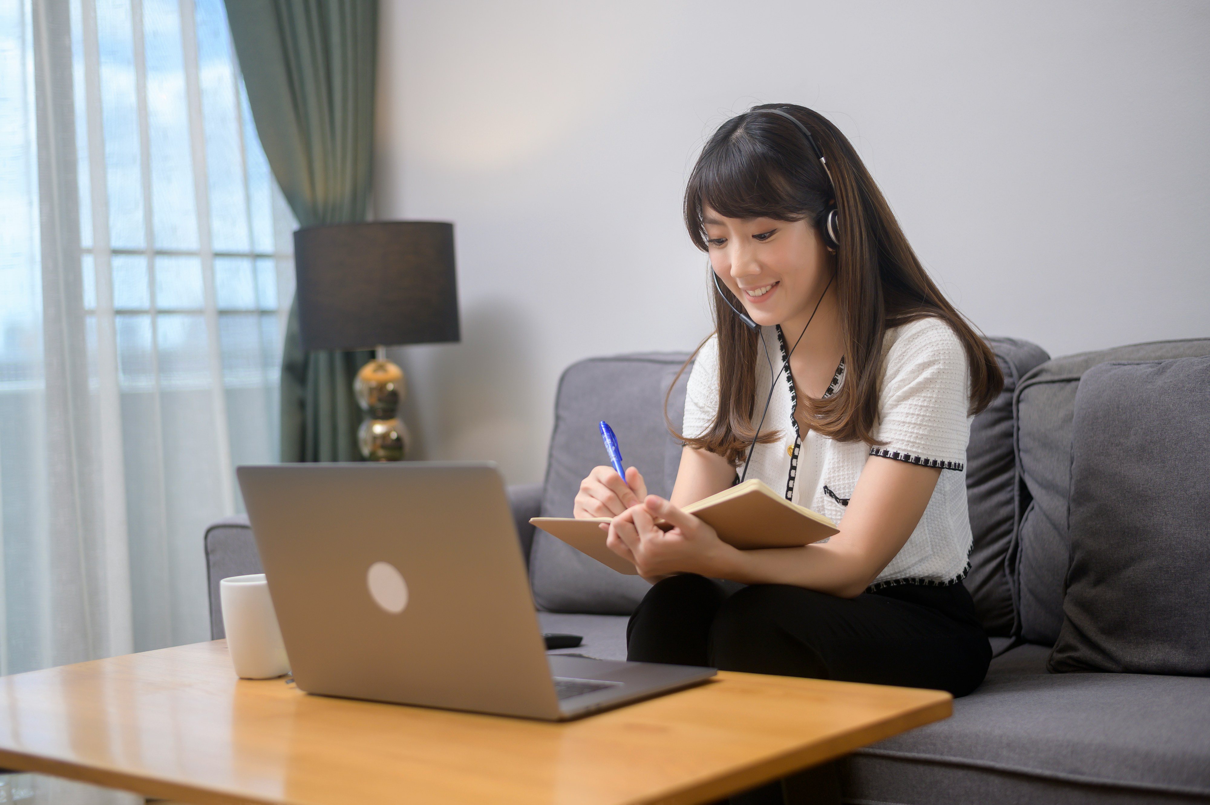 Learn@Home - Frau lernt zu Hause mit Laptop und Notizbuch für ihre Online-Ausbildung
