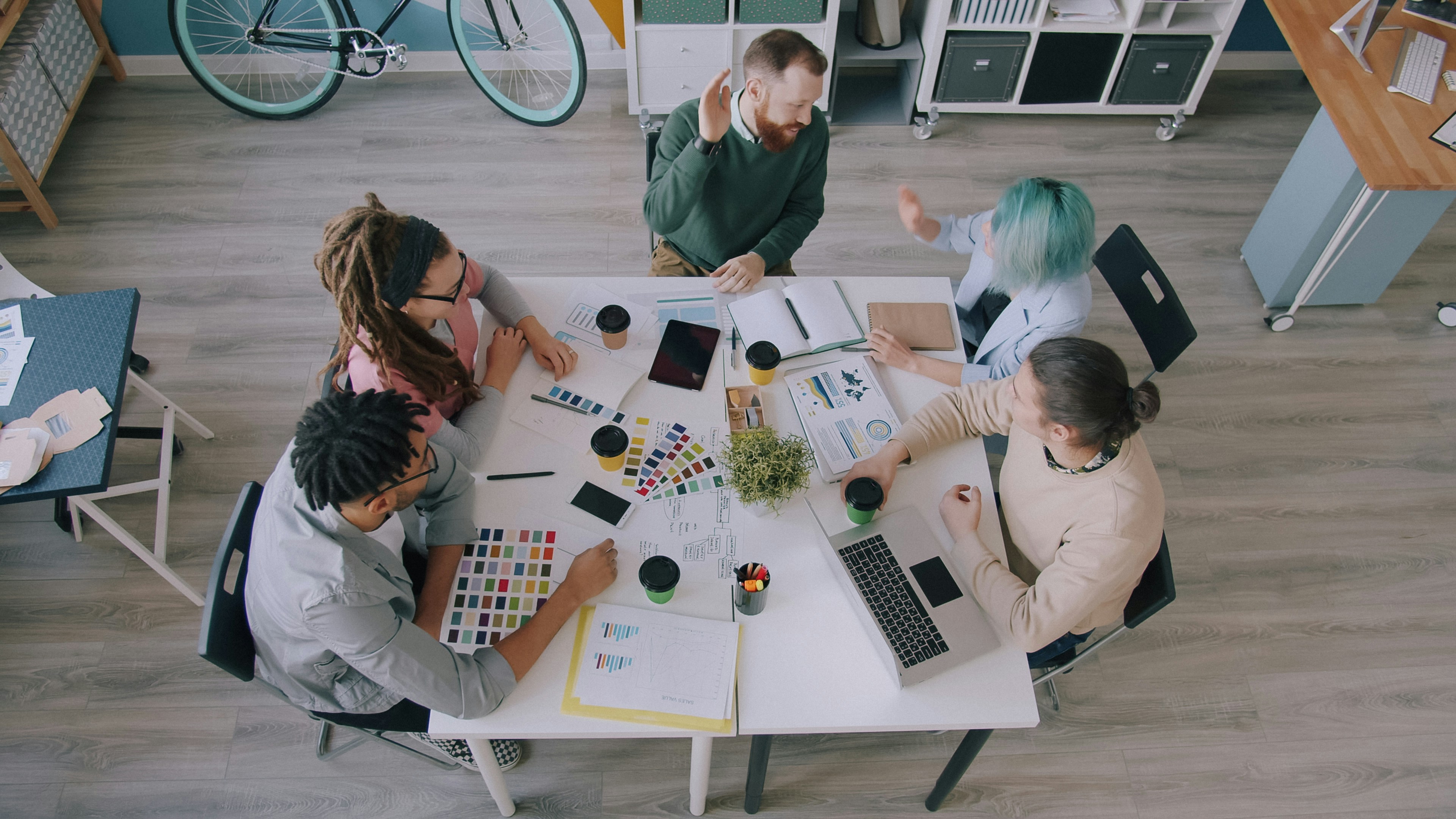Learn@Home - Kreatives Team arbeitet gemeinsam an einem Tisch an Ideen, Konzepten und visuellen Entwürfen.