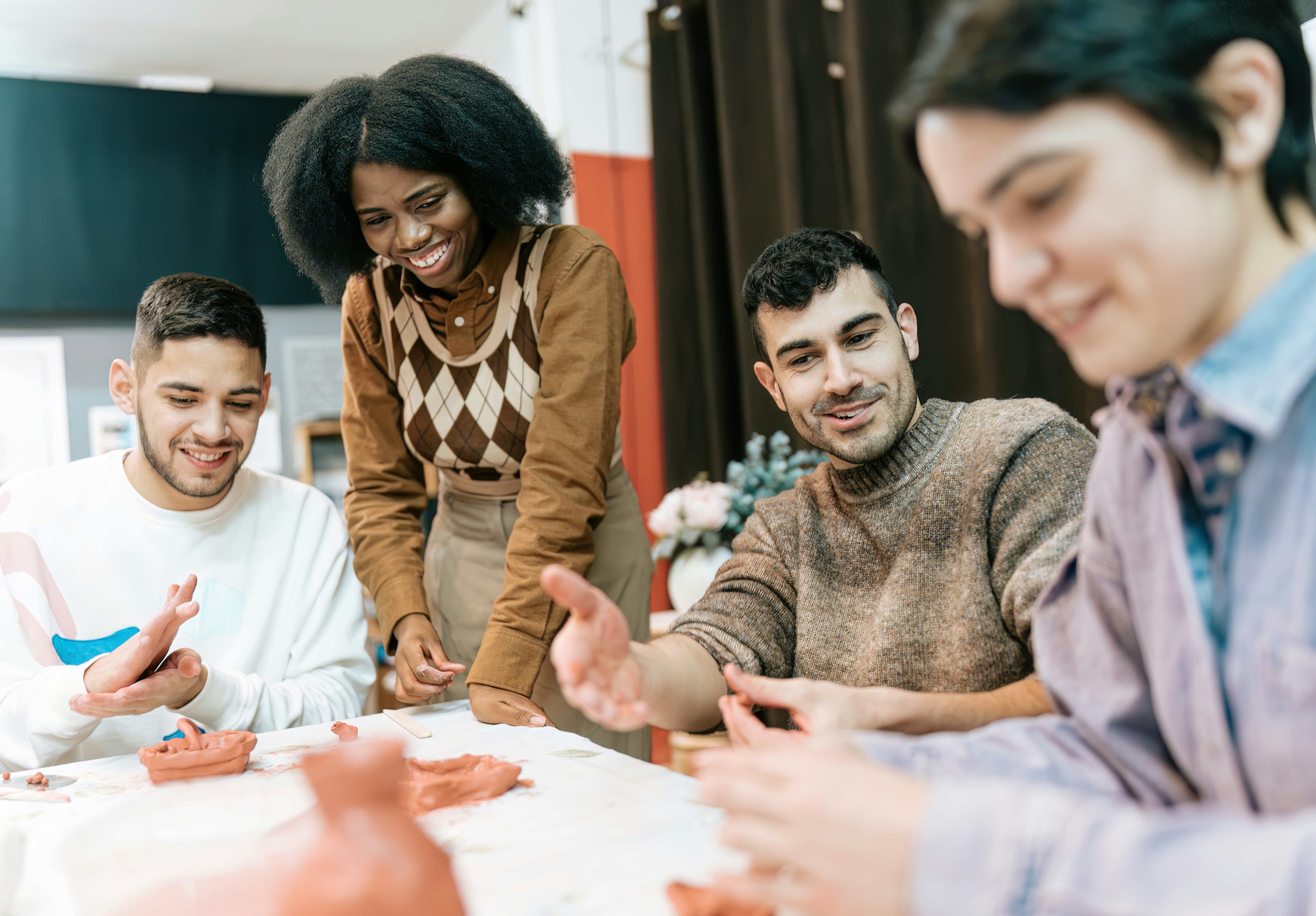 Learn@Home - Gruppe junger Erwachsener arbeitet gemeinsam kreativ und gestaltet mit Ton in einer entspannten Atmosphäre.